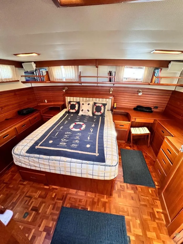 Slide: The Image of Luxurious 1999 Grand Banks 42 Motoryacht bedroom with wood paneling and nautical-themed bedding. - 11