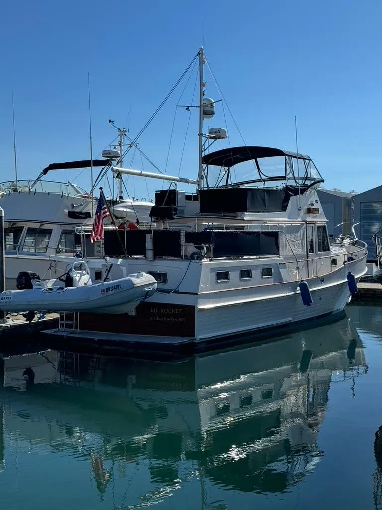 Slide: The Image of 1999 Grand Banks 42 Motoryacht docked with tender, reflecting on calm water. - 20