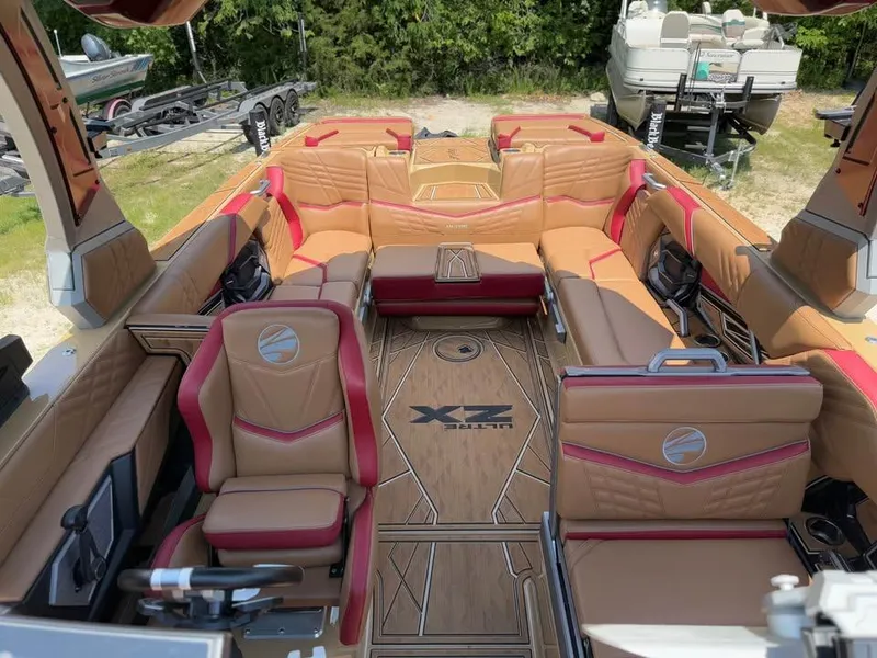 Slide: The Image of 2024 Tigé Ultré 25ZX boat interior with luxurious tan and red seating, wood-patterned flooring. - 16