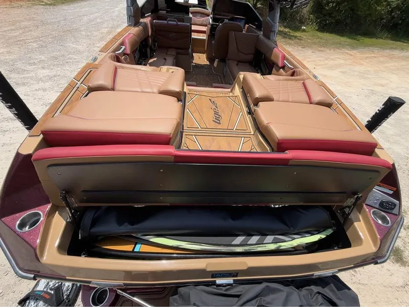 Slide: The Image of 2024 Tigé Ultré 25ZX boat interior with tan and red seating, open storage compartment. - 17