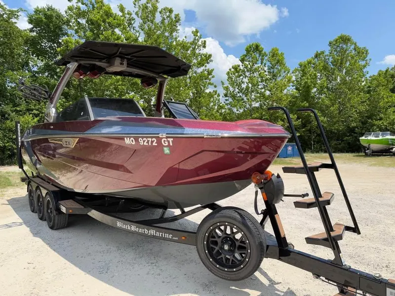 Slide: The Image of 2024 Tigé Ultré 25ZX boat on trailer, parked outdoors with trees in background. - 3