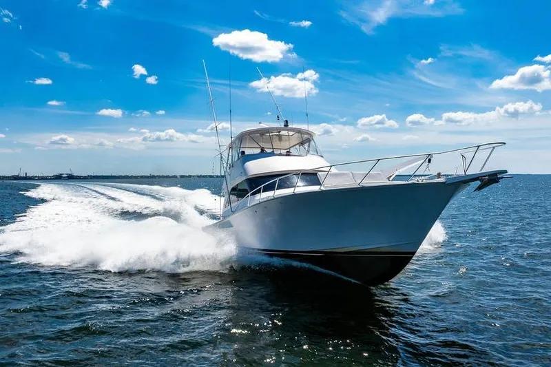 Slide: The Image of 2006 Viking 56 Convertible yacht cruising on open water under a clear blue sky. - 102