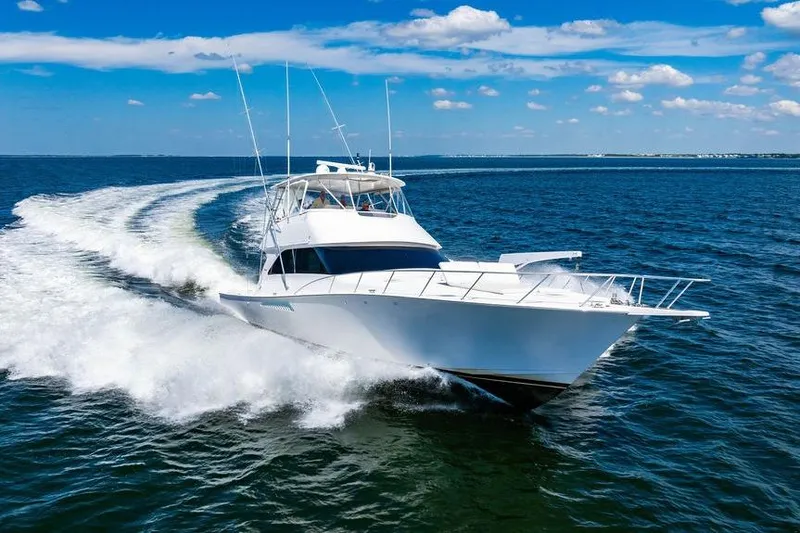 Slide: The Image of 2006 Viking 56 Convertible yacht cruising on open water under a clear blue sky. - 104