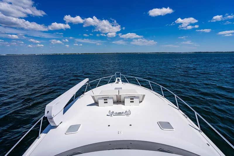Slide: The Image of 2006 Viking 56 Convertible yacht cruising on open water under a clear blue sky. - 62