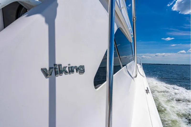 Slide: The Image of 2006 Viking 56 Convertible yacht cruising on open water under clear blue sky. - 65