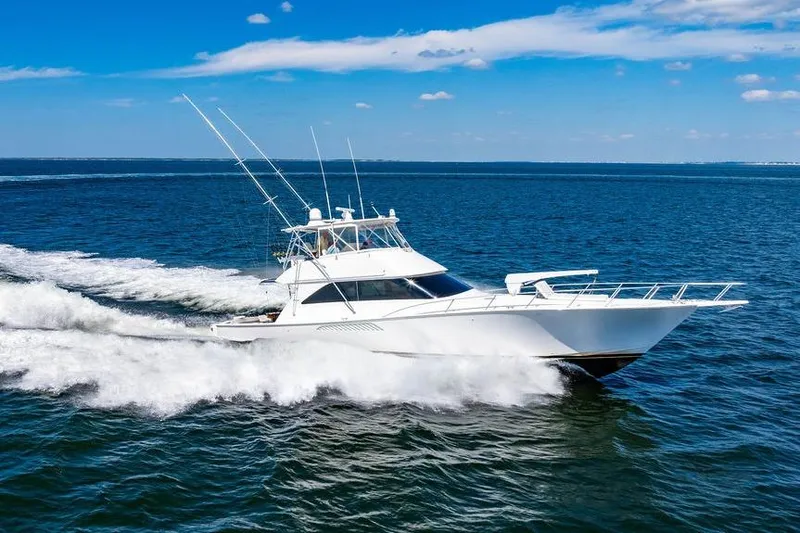 Slide: The Image of 2006 Viking 56 Convertible yacht cruising on open blue sea under clear sky. - 87