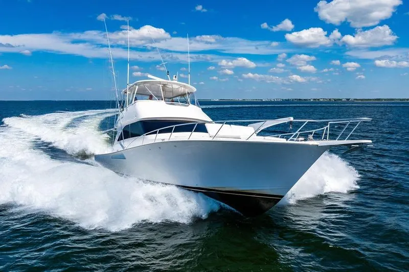 Slide: The Image of 2006 Viking 56 Convertible yacht cruising on open water under a clear blue sky. - 90
