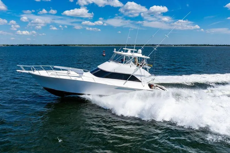 Slide: The Image of 2006 Viking 56 Convertible yacht cruising on open water under a clear blue sky. - 96