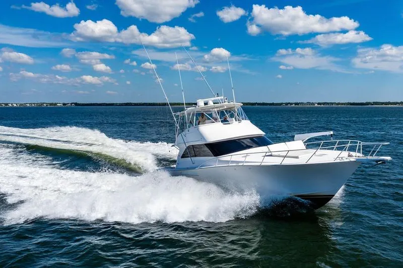 Slide: The Image of 2006 Viking 56 Convertible yacht cruising on open water under a clear blue sky. - 98