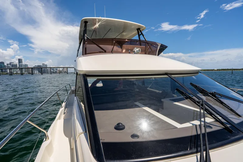 Slide: The Image of 2023 Prestige 520 yacht cruising on a sunny day with city skyline in background. - 32