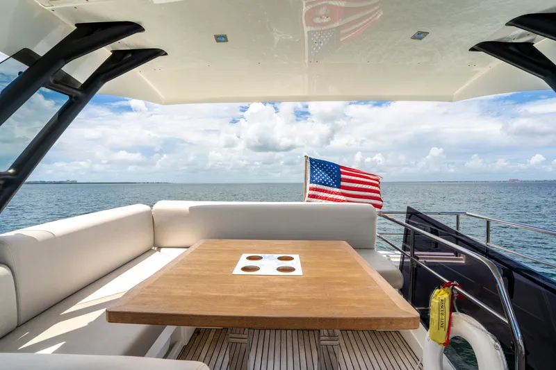 Slide: The Image of Luxurious 2023 Prestige 520 yacht deck with seating, table, and American flag on open sea. - 35