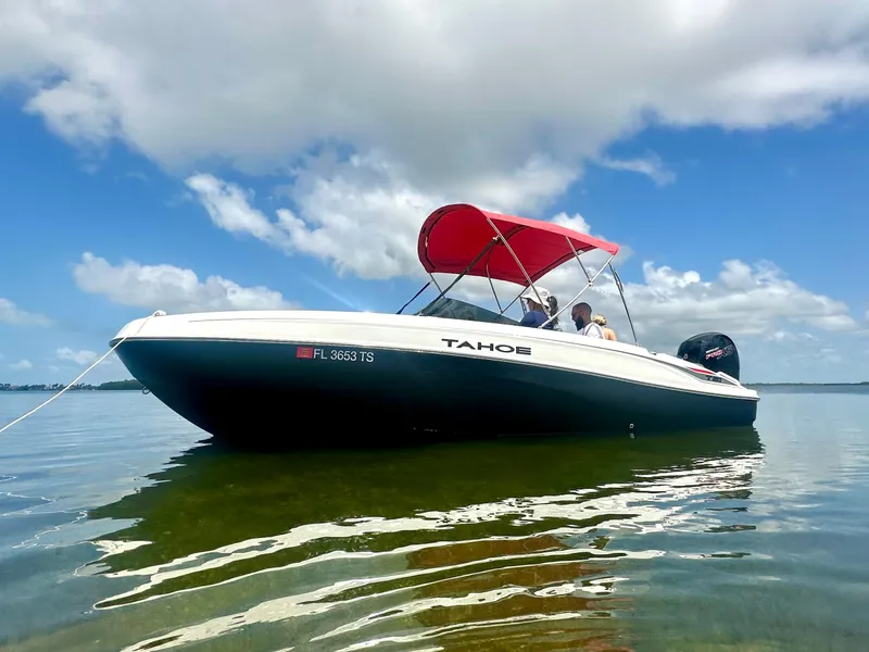 The Image of 2024 Tahoe T21 boat with red canopy on calm water under blue sky. - 0