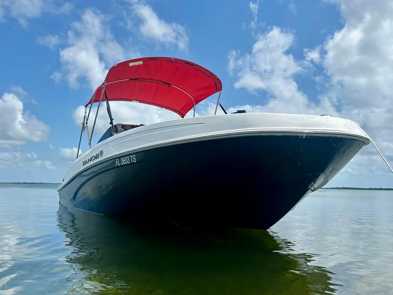 Slide: The Image of 2024 Tahoe T21 boat with red canopy on calm water under blue sky. - 9