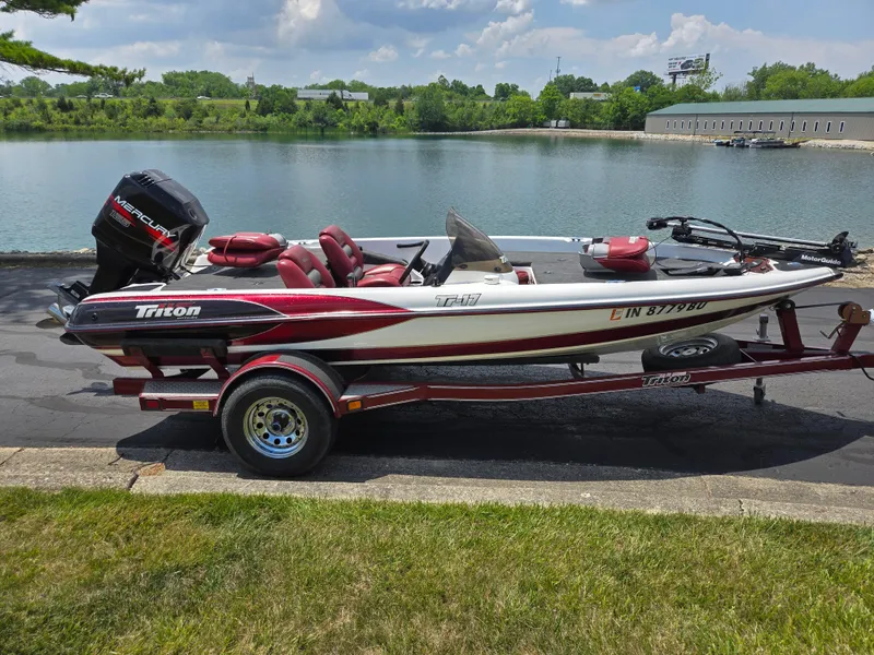 Slide: The Image of 1998 Triton Tr-17 boat on trailer by a lake, featuring a Mercury outboard motor. - 11