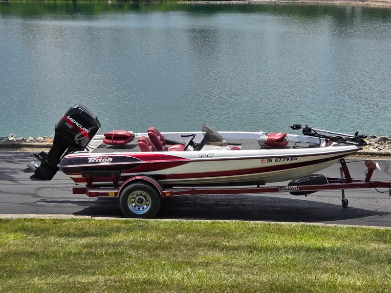 Slide: The Image of 1998 Triton Tr-17 boat on trailer by a lake, featuring a Mercury outboard motor. - 12