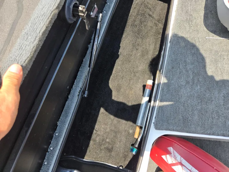 Slide: The Image of 1998 Triton Tr-17 boat storage compartment with carpeted interior and hydraulic lift support. - 17