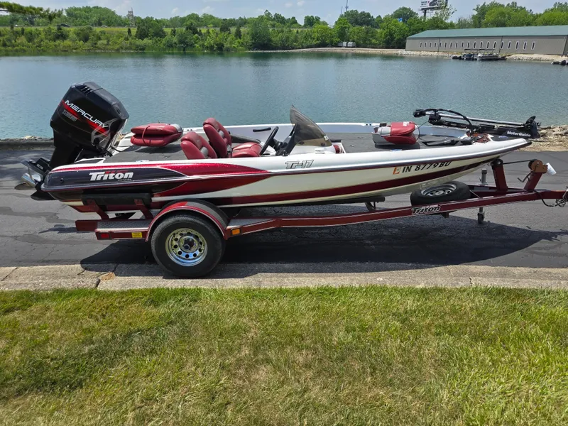Slide: The Image of 1998 Triton Tr-17 boat on trailer by a lake, featuring a Mercury outboard motor. - 2