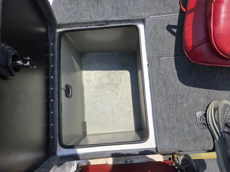 Slide: The Image of Open storage compartment in a 1998 Triton Tr-17 boat with red seating and gray carpet. - 23