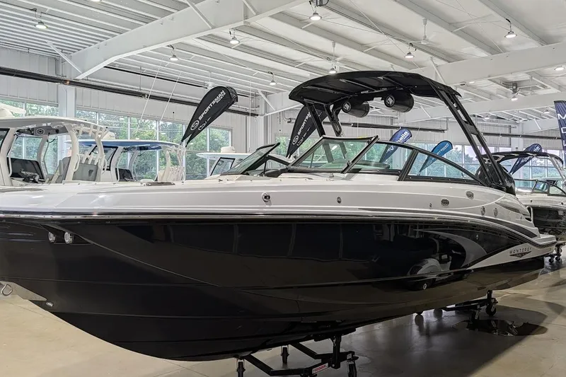 Slide: The Image of 2026 Monterey M-65 boat displayed in a showroom, featuring sleek black and white design. - 1