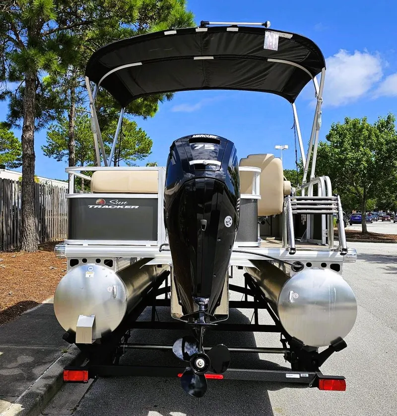Slide: The Image of 2025 Sun Tracker Party Barge 18 DLX pontoon boat with Mercury 75 engine, parked outdoors. - 3