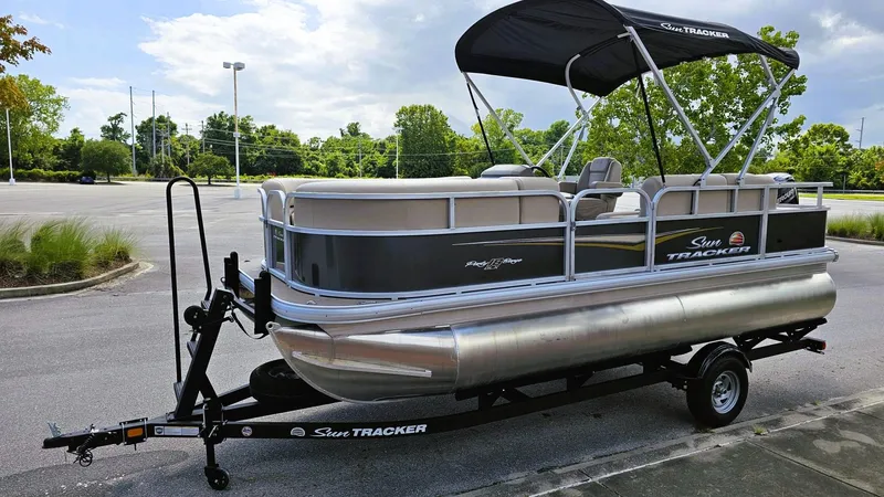 Slide: The Image of 2025 Sun Tracker Party Barge 18 DLX pontoon boat on trailer in parking lot. - 6