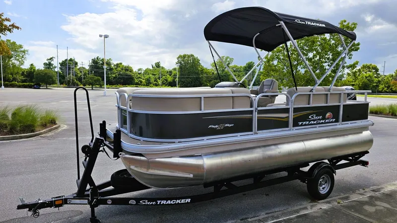 Slide: The Image of 2025 Sun Tracker Party Barge 18 DLX pontoon boat on trailer in parking lot. - 7