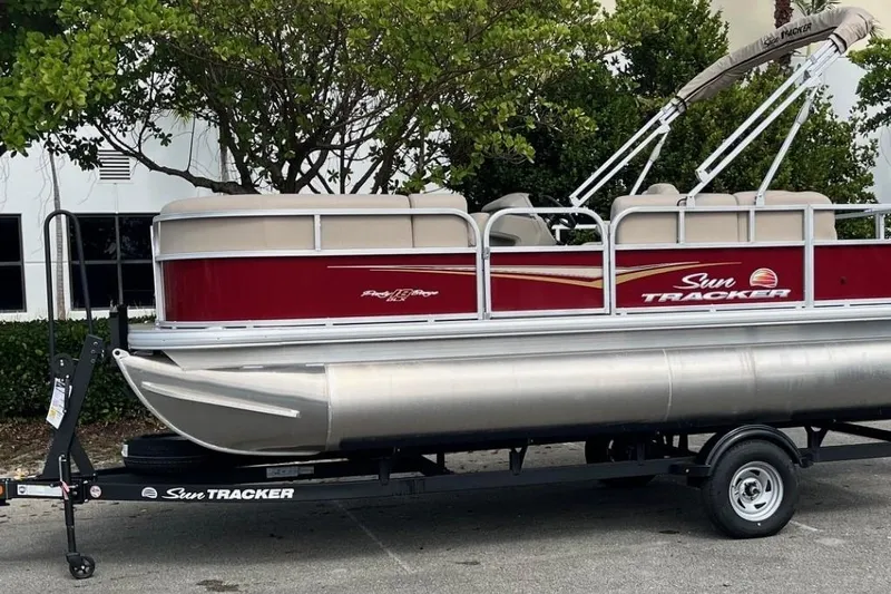 The Image of 2025 Sun Tracker Party Barge 18 DLX pontoon boat on trailer, parked outdoors. - 0