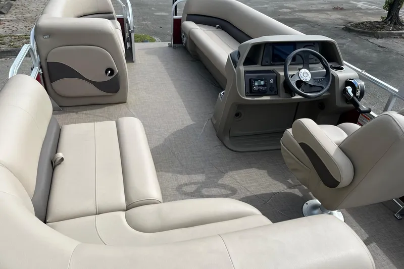 Slide: The Image of 2025 Sun Tracker Party Barge 18 DLX interior with beige seating and modern helm. - 17