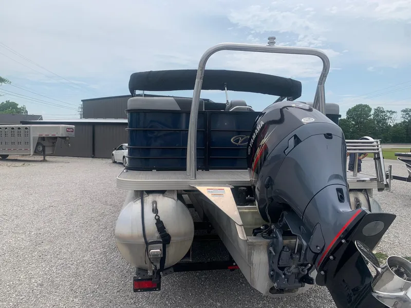 Slide: The Image of 2019 Veranda Relax VR25RC pontoon boat on trailer, blue exterior, parked on gravel. - 4