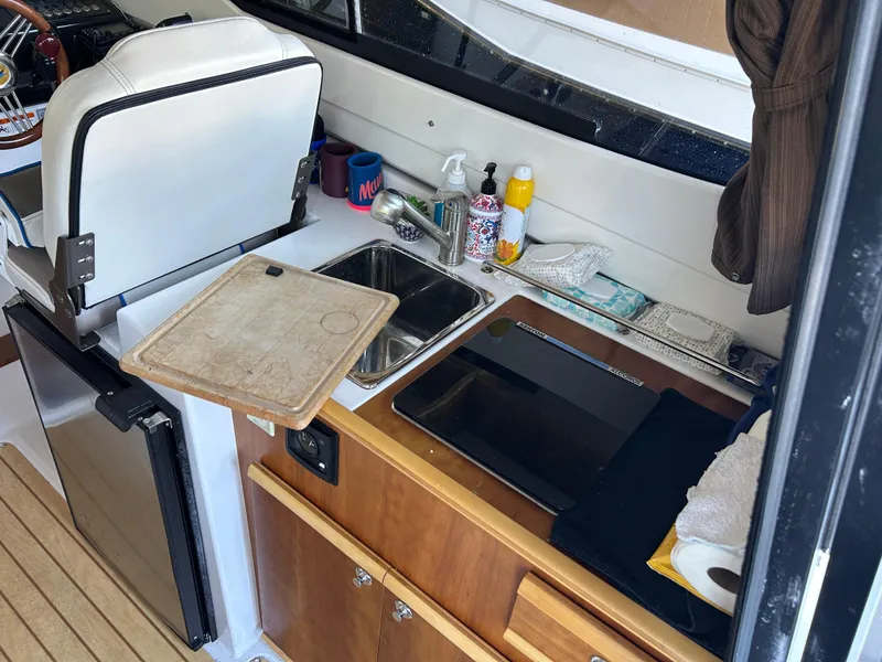 Slide: The Image of Compact kitchen area in a 2017 Cutwater C-242 Coupe boat with sink and cutting board. - 10