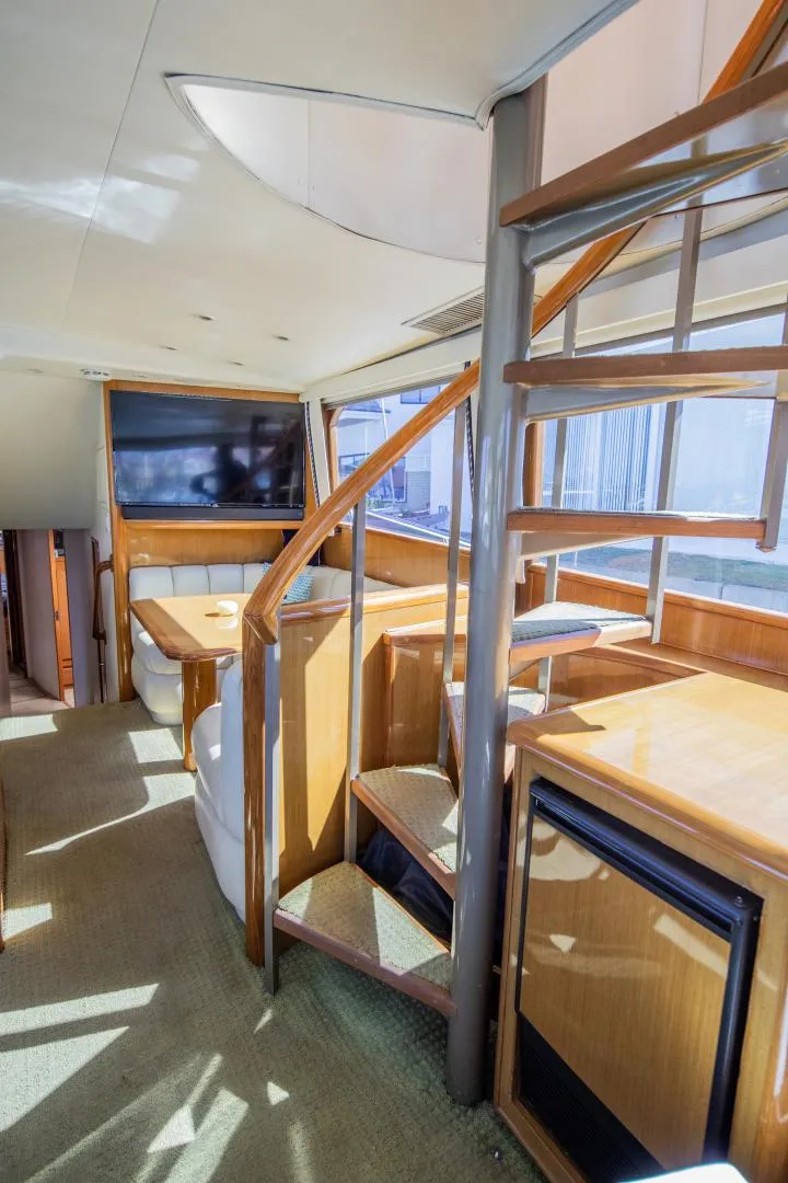 Slide: The Image of Interior of 1999 Viking 58 Enclosed Bridge yacht with spiral staircase and seating area. - 12