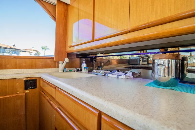Slide: The Image of 1999 Viking 58 Enclosed Bridge yacht kitchen with wooden cabinets and countertop. - 14