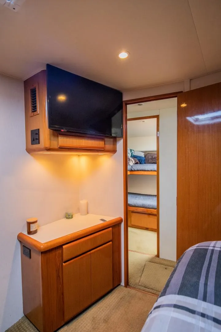Slide: The Image of 1999 Viking 58 Enclosed Bridge interior with TV, cabinet, and bunk beds. - 23