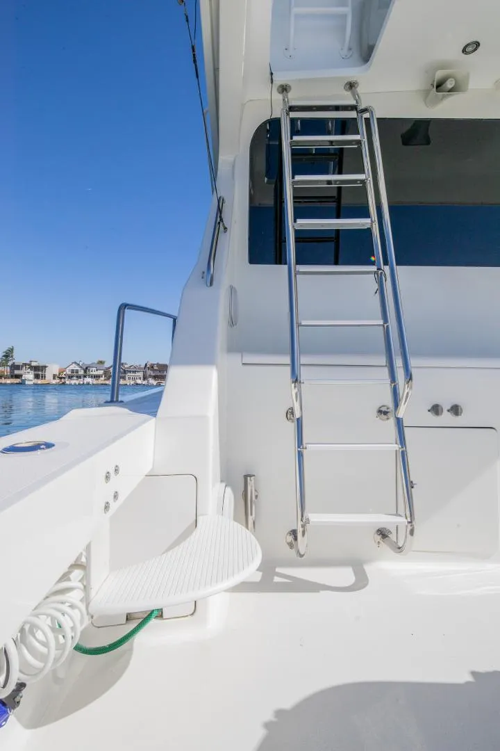 Slide: The Image of 1999 Viking 58 Enclosed Bridge yacht with ladder and deck, under clear blue sky. - 33