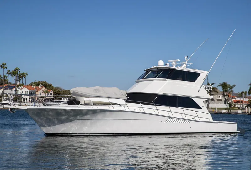 Slide: The Image of 1999 Viking 58 Enclosed Bridge yacht on calm water, clear sky background. - 4