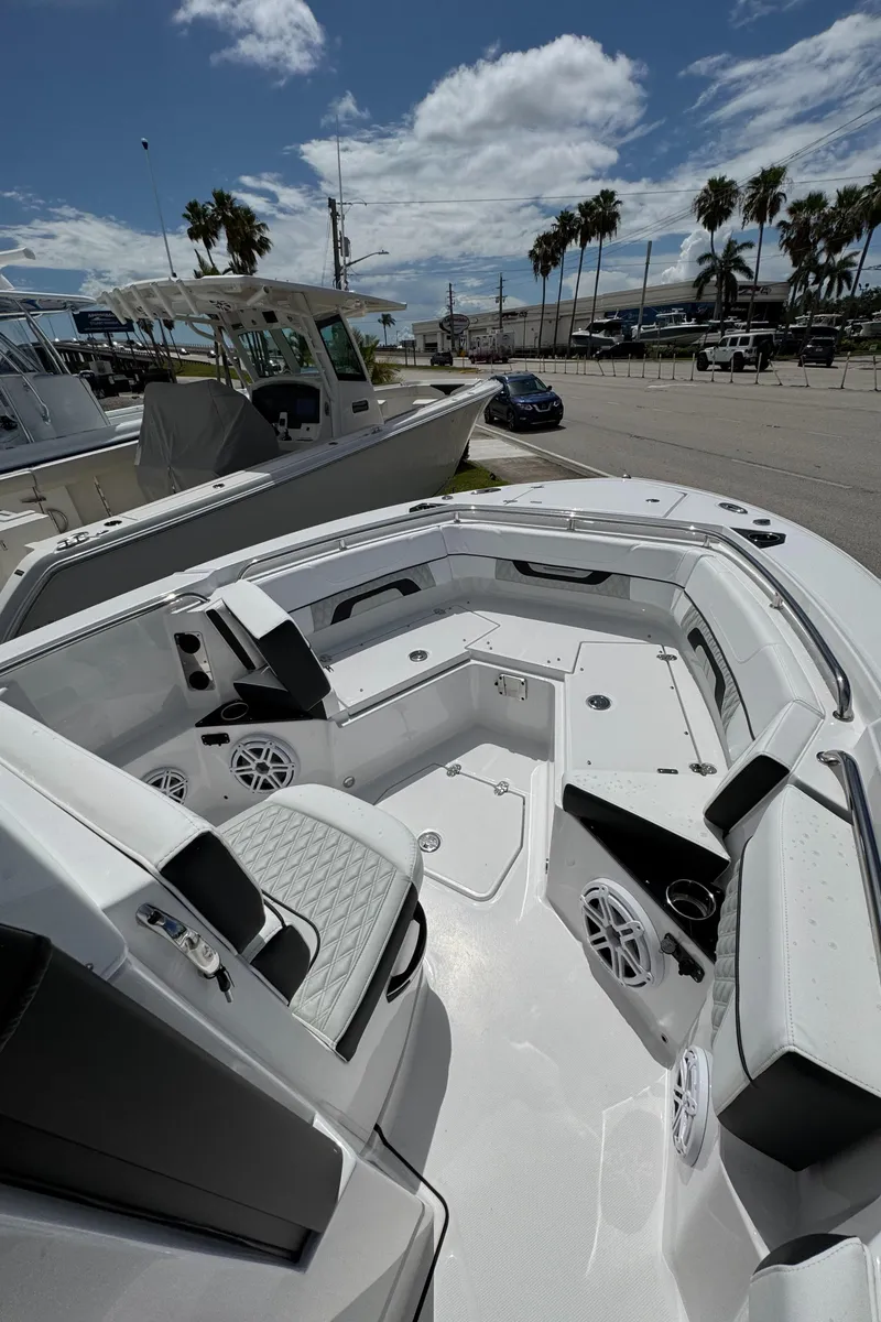 Slide: The Image of 2025 Blackfin 252 CC boat interior with seating, speakers, and cup holders under a sunny sky. - 13