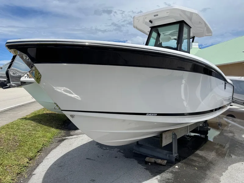Slide: The Image of 2025 Blackfin 252 CC boat displayed outdoors on a sunny day. - 2