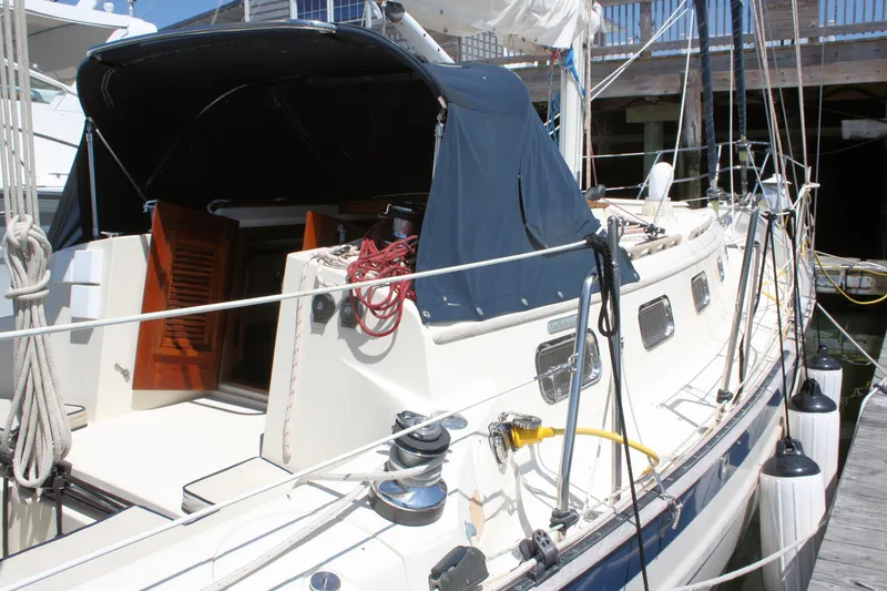 Slide: The Image of 2004 Pacific Seacraft 31 sailboat docked, featuring a covered cockpit and open cabin doors. - 2