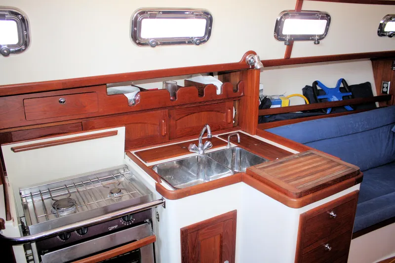 Slide: The Image of Interior of 2004 Pacific Seacraft 31 sailboat, featuring a compact kitchen with stove and sink. - 32