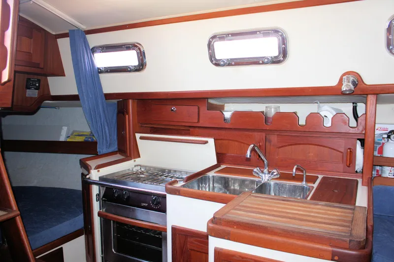 Slide: The Image of Interior of 2004 Pacific Seacraft 31 sailboat, featuring a compact kitchen with stove and sink. - 33