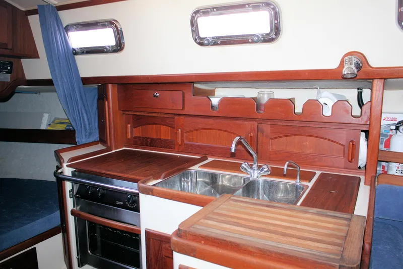 Slide: The Image of Interior of 2004 Pacific Seacraft 31 sailboat galley with wooden cabinetry and stainless steel sink. - 34