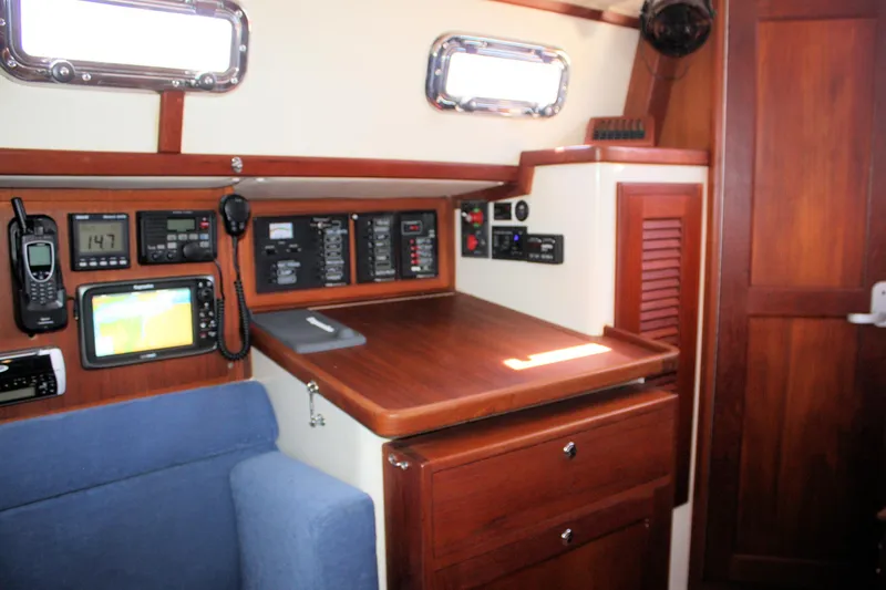 Slide: The Image of Navigation station inside a 2004 Pacific Seacraft 31 sailboat, featuring control panels and seating. - 35