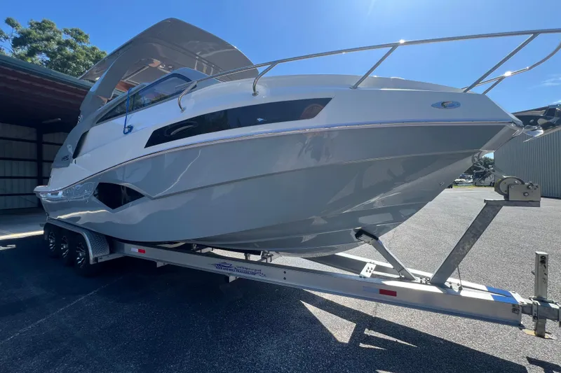 Slide: The Image of 2024 NX Boats 290 Exclusive on trailer, sleek design under sunny sky. - 10