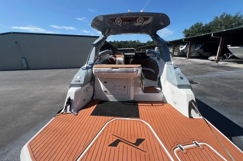 Slide: The Image of 2024 NX Boats 290 Exclusive with teak deck, docked in a marina under clear skies. - 15