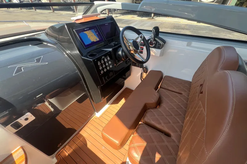 Slide: The Image of 2024 NX Boats 290 Exclusive cockpit with brown leather seats and modern dashboard. - 23