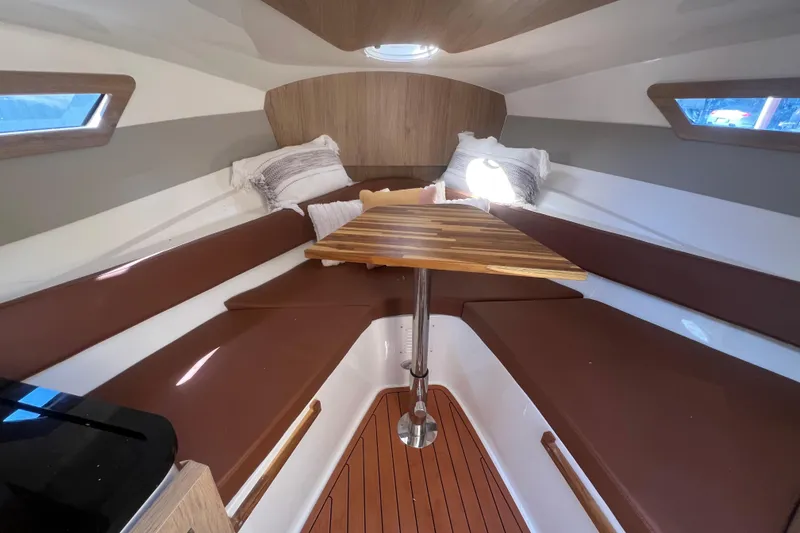 Slide: The Image of 2024 NX Boats 290 Exclusive cabin interior with brown seating and wooden table. - 29
