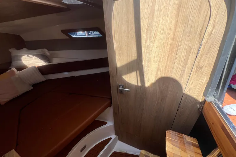 Slide: The Image of Interior cabin of 2024 NX Boats 290 Exclusive with wooden door and cozy seating area. - 31