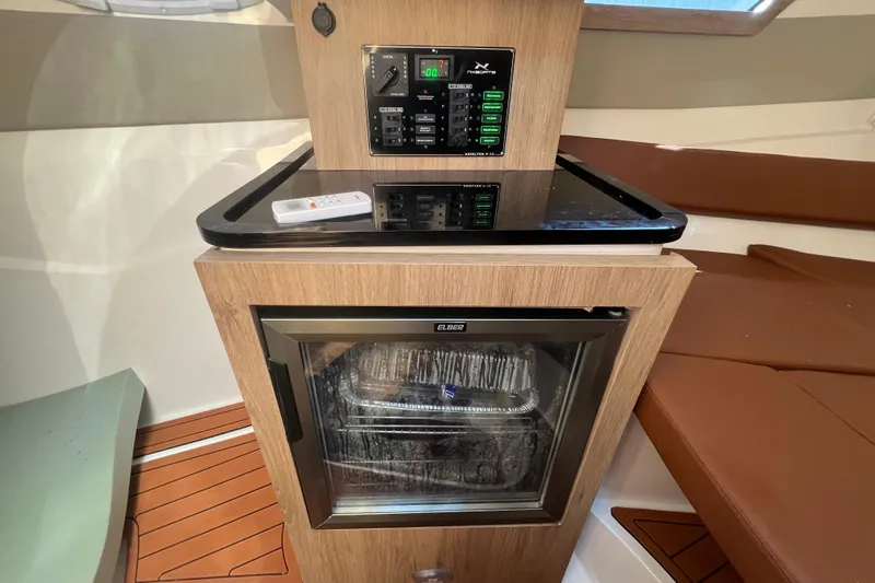 Slide: The Image of 2024 NX Boats 290 Exclusive interior with control panel and mini fridge. - 38
