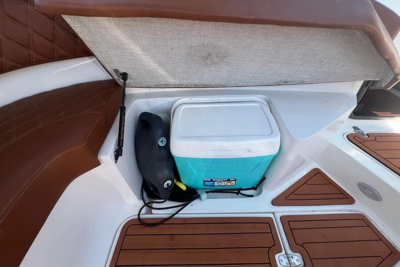 Slide: The Image of 2024 NX Boats 290 Exclusive storage area with cooler and brown seating. - 41