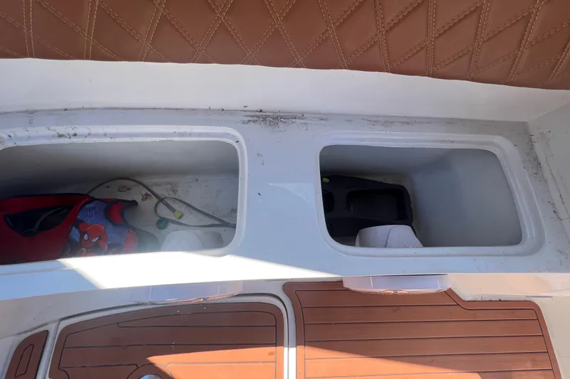 Slide: The Image of 2024 NX Boats 290 Exclusive storage compartments with brown leather seating and wooden flooring. - 45